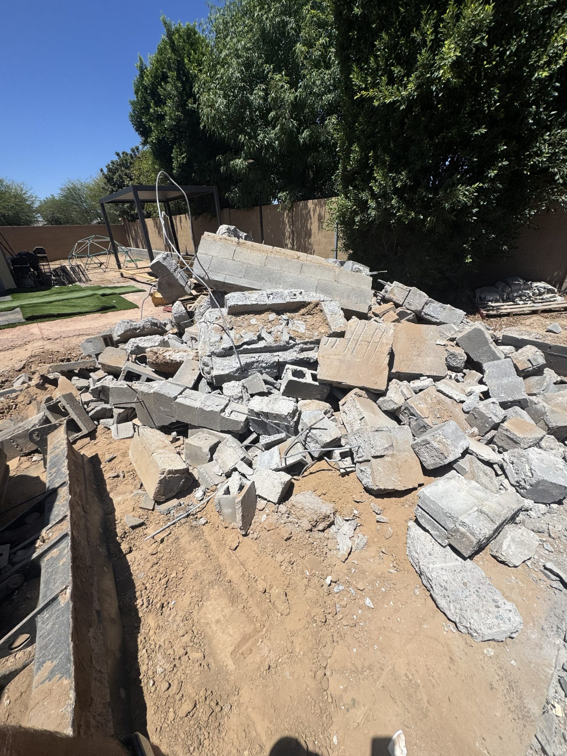 Residential demolition project in Mesa, AZ with heavy equipment removing debris from a structure during site cleanup and demolition work.