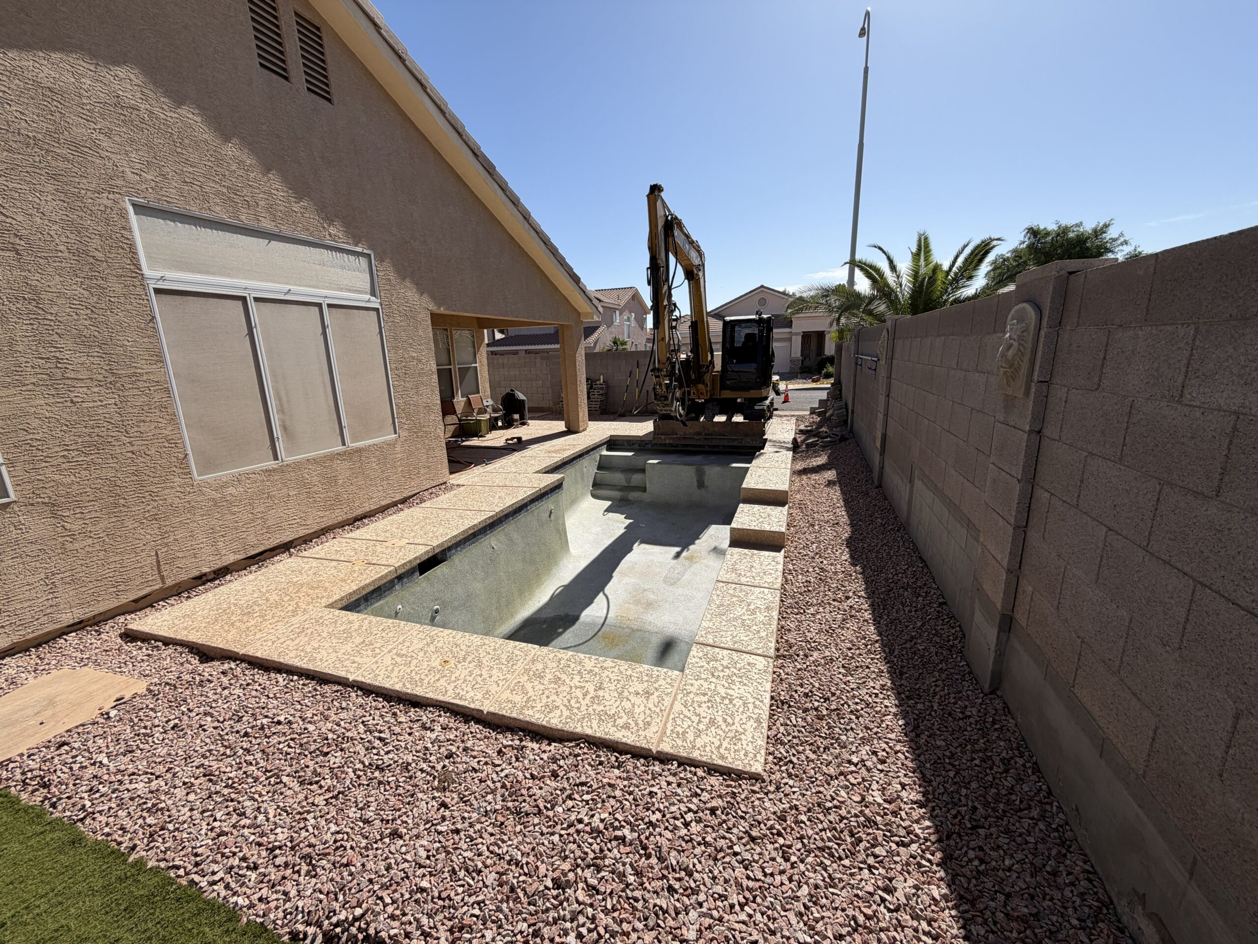 Swimming pool demolition project in Mesa, AZ with heavy equipment removing an old backyard pool during residential demolition work.