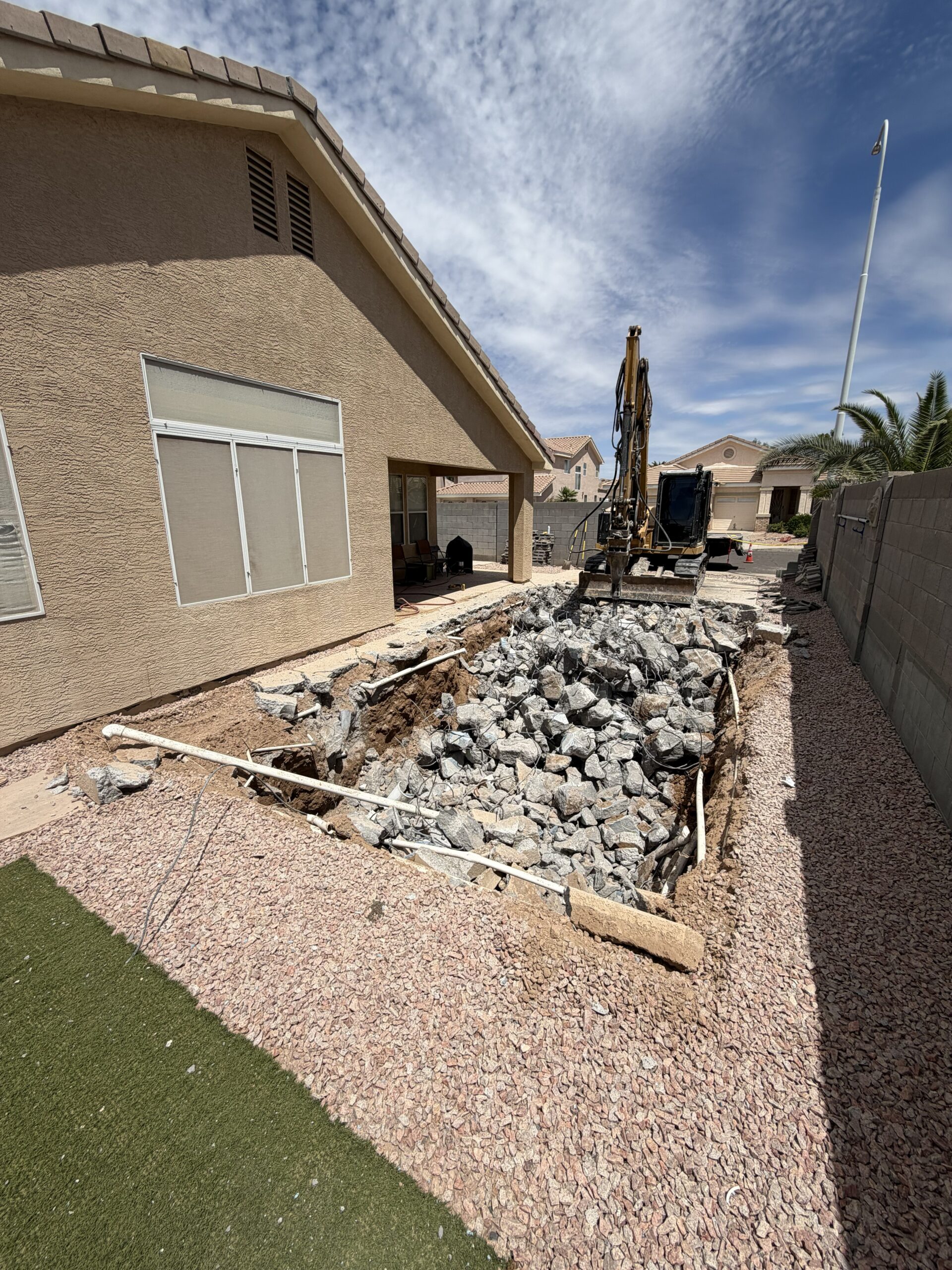 Professional pool removal services in Mesa, Arizona showing excavation equipment demolishing a residential swimming pool.