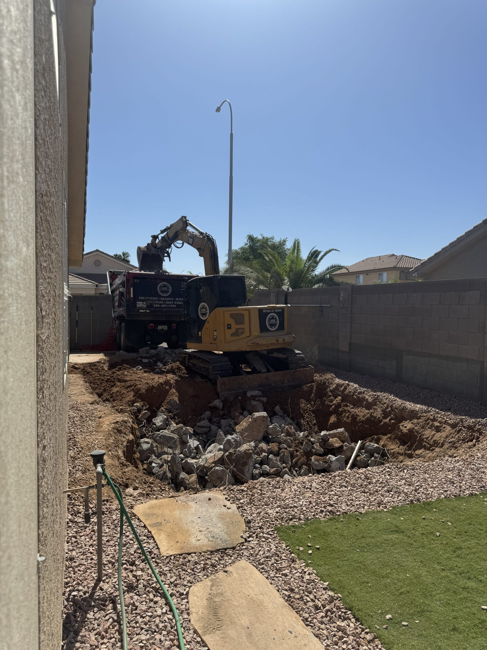 Full pool removal project in Mesa, AZ with concrete demolition and backyard excavation in progress.